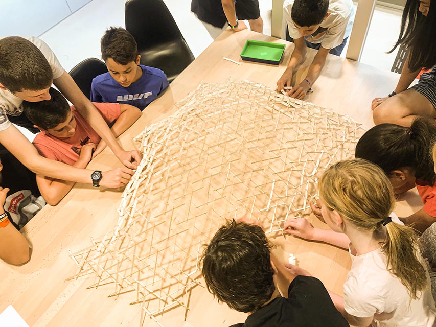 Imagen de un grupo de niños construyendo una 
                      gran estructura con módulos de madera.