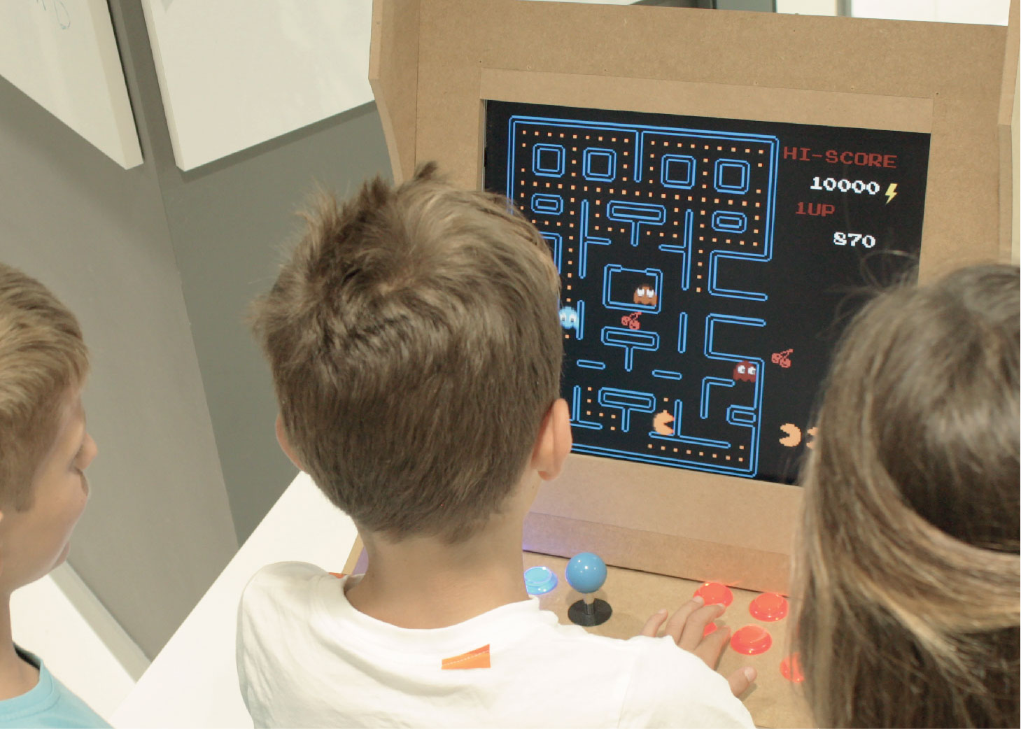 Tres niños jugando a un juego de arcade.